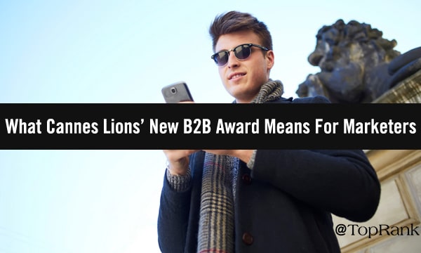 B2B marketer holding cellphone in front of large stone lion sculpture image.