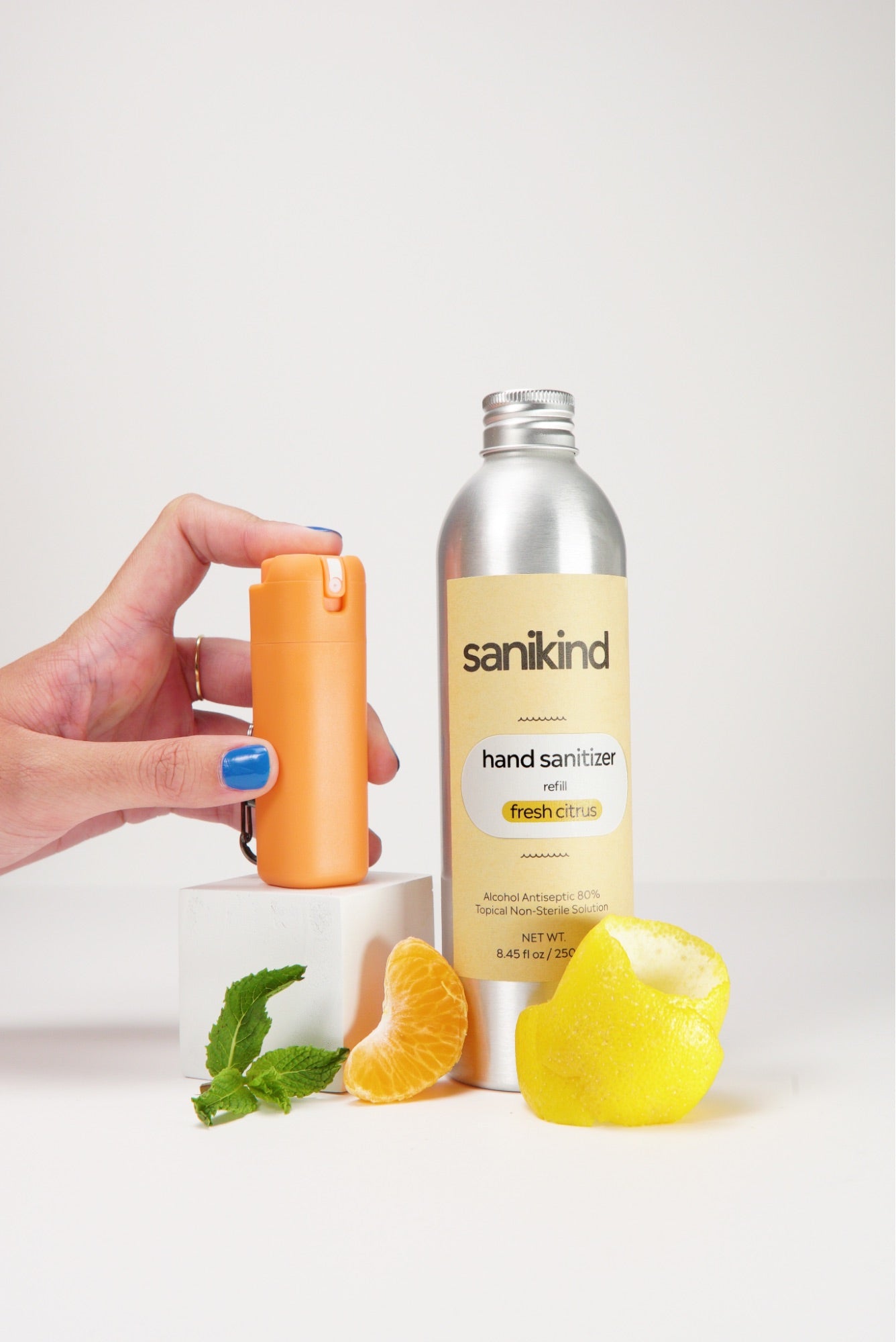 A sanitizer bottle against a white background with a hand model holding an orange Snikind dispenser.