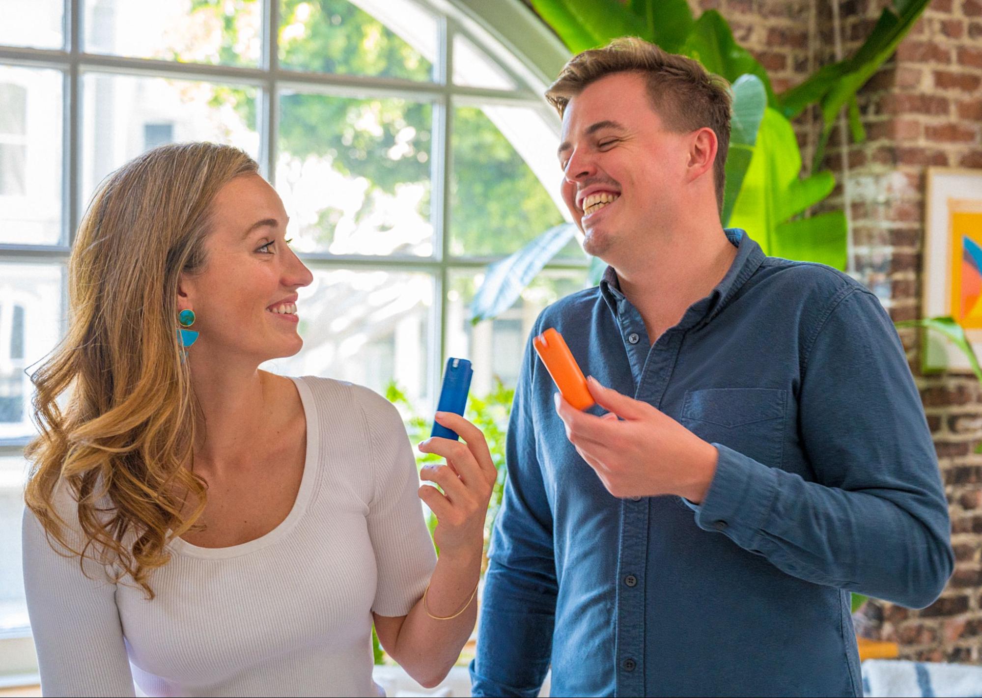 Cofounders of Sanikind, Martica Wakeman and Miles Pepper in an office setting holding up refillable Sanikind sanitizer capsules.