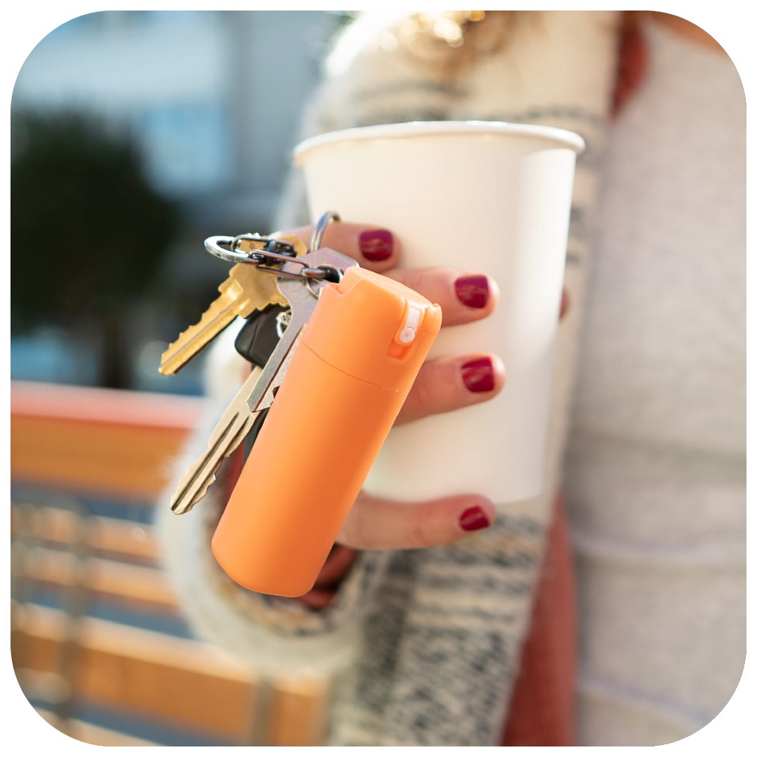 A hand model holds a coffee cup along with keys and a Sanikind dispenser attached. 