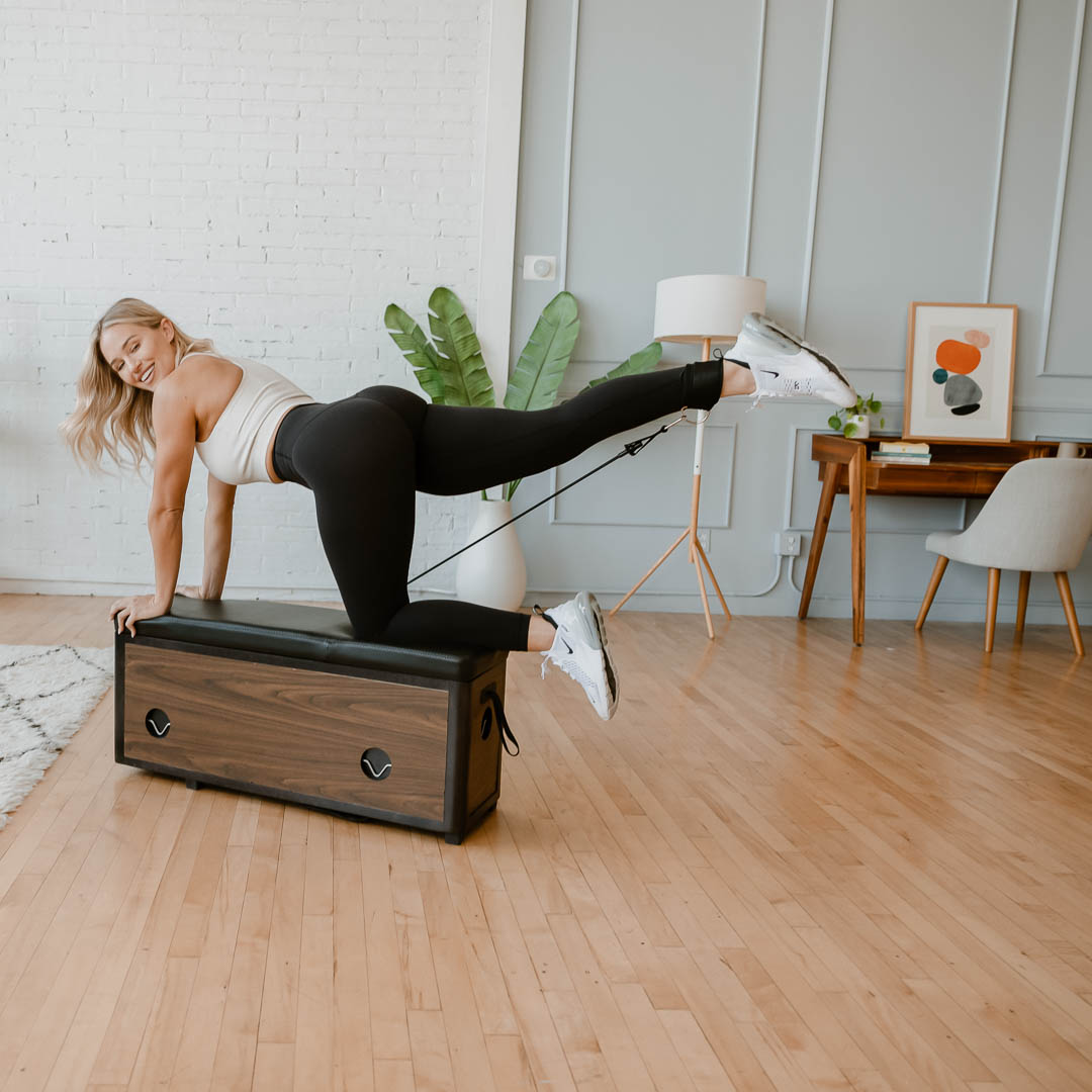 A model uses the Zeno Gym workout bench in an living room setting.