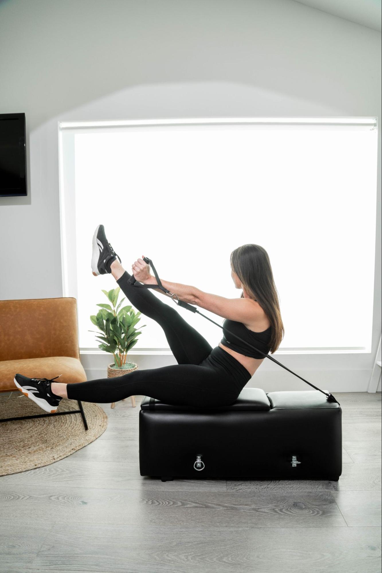 A model uses a workout bench by Zeno Gym next to a couch in a living room setting.