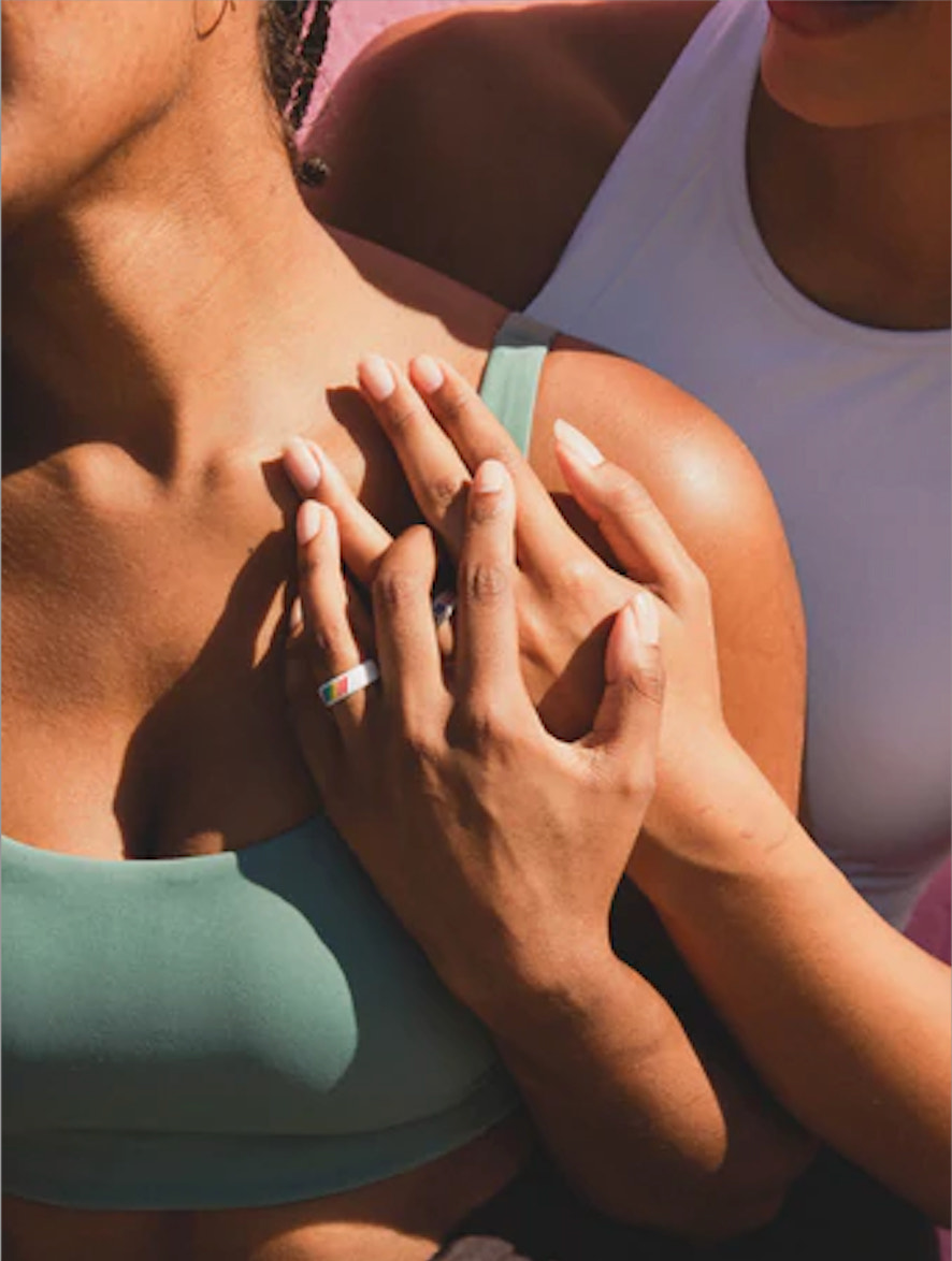 Two women hold hands and one is wearing a QALO ring
